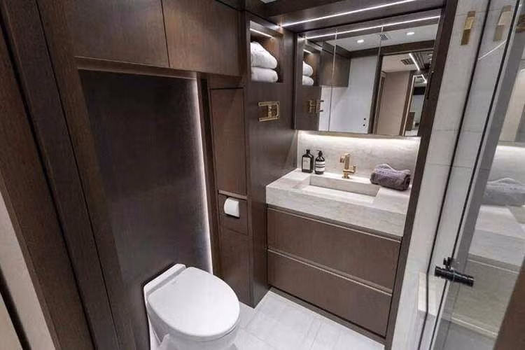 Không gian nhà vệ sinbh của chiếc xe này bao gồm buồng tắm đứng rộng rãi được lát gạch chuyên dụng, bàn đá tự nhiên, bồn cầu hiện đại và hệ thống tủ kệ tăng cường khả năng lưu trữ.