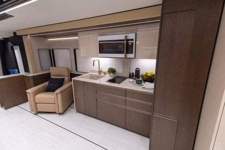 Nhà bếp của căn nhà di động Loki Prevost 2026 sở hữu đầy đủ tiện nghi với mặt bếp bằng đá tự nhiên, tủ lạnh kích thước lớn, máy rửa bát và bếp điện.