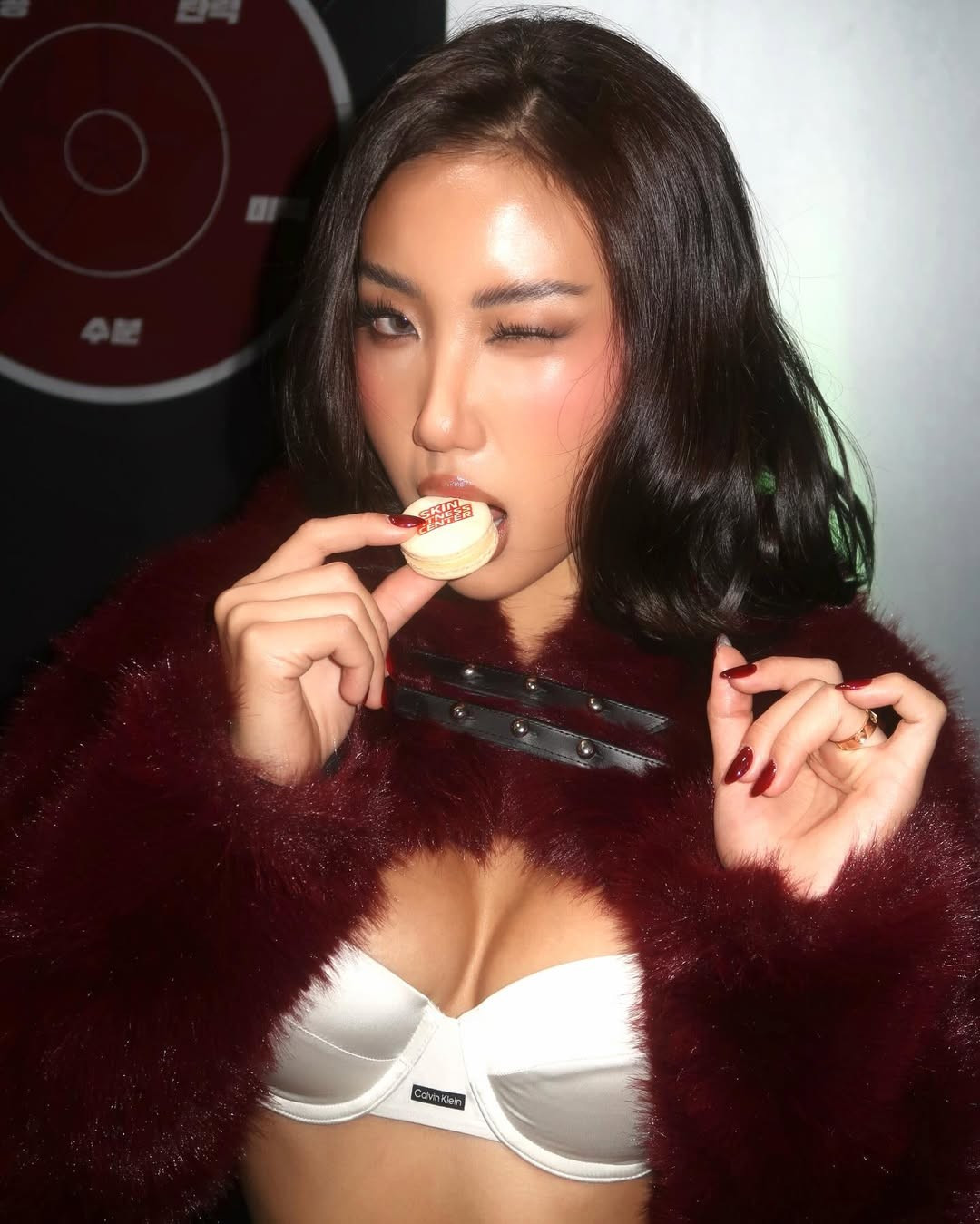 Thiết kế áo khoác lông tông màu trầm được khoác hờ bên ngoài, kết hợp cùng bra trắng và chân váy ngắn, tạo nên tổng thể vừa cá tính vừa quyến rũ.