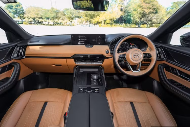 Khoang nội thất của CX-80 được bố trí 6 chỗ ngồi với hàng ghế giữa là cặp ghế thương gia tích hợp sưởi, thông gió và ngả điện, có bệ tì tay riêng. Ghế lái và ghế phụ phía trước đều chỉnh điện 10 hướng, ghế lái có thêm chức năng nhớ vị trí và cá nhân hóa người dùng.