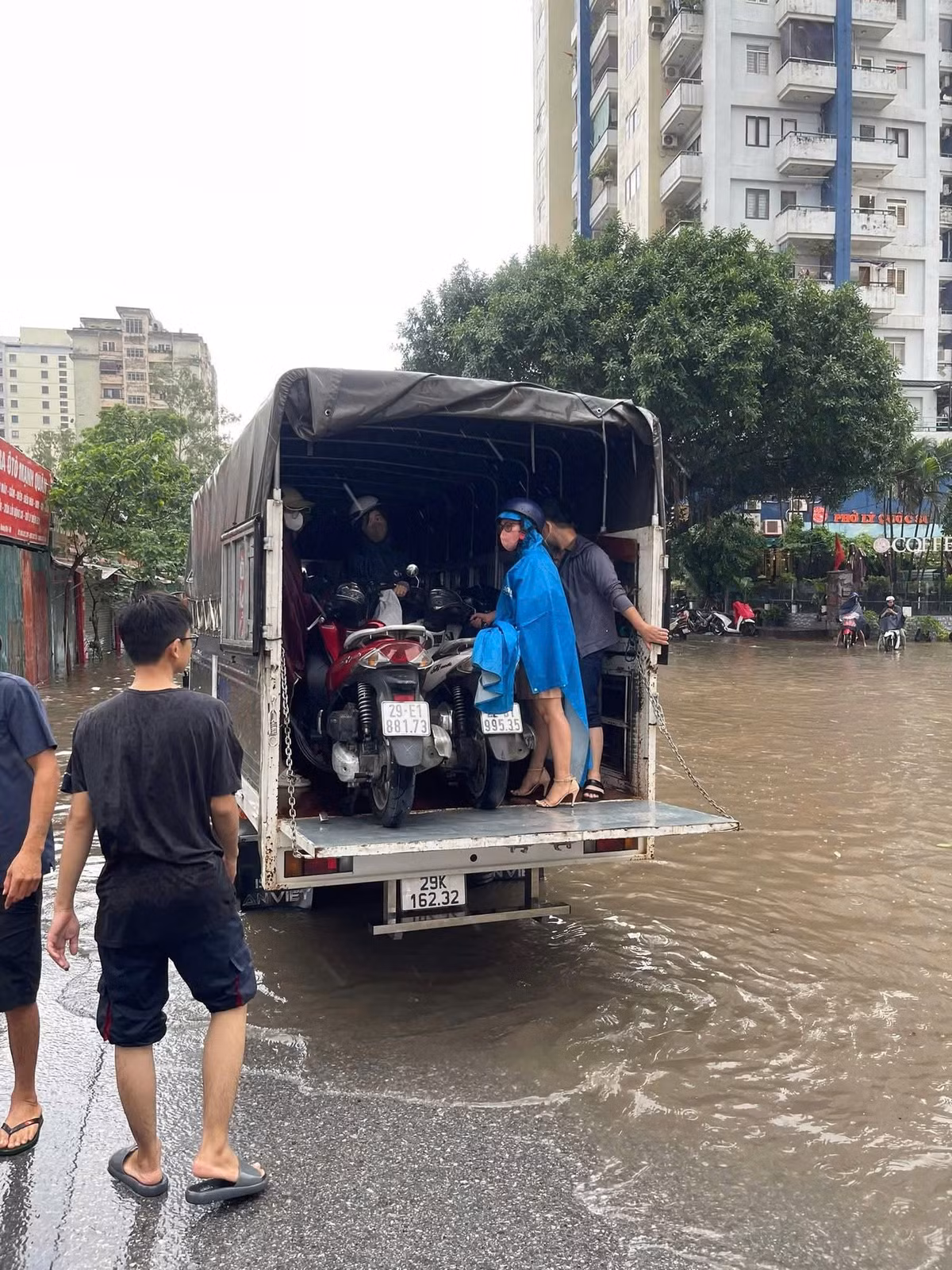 Hình ảnh người dân giúp đỡ nhau đưa xe máy qua khu vực bị ngập sâu tại Hà Nội sáng ngày 26/8.