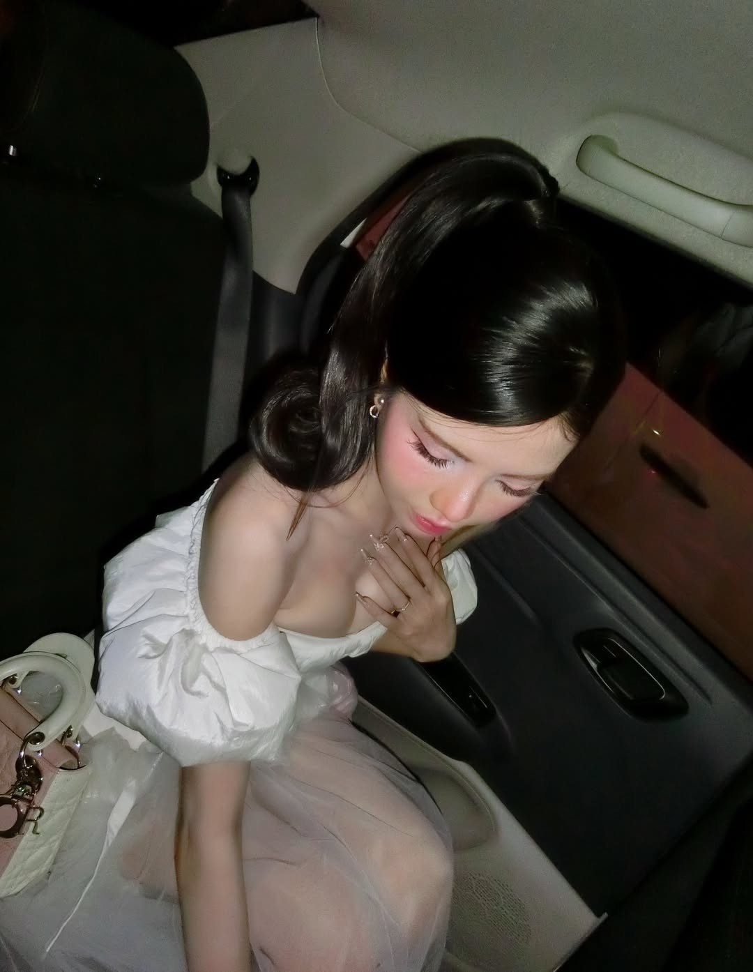 Bộ váy trắng trễ vai ôm sát phần thân trên, kết hợp cùng chất liệu mềm mại, giúp tôn lên đường cong cơ thể một cách tinh tế. Không cần tạo dáng cầu kỳ, chỉ với vài góc máy chụp trong không gian xe hơi về đêm, nữ MC vẫn toát lên sức hút riêng.