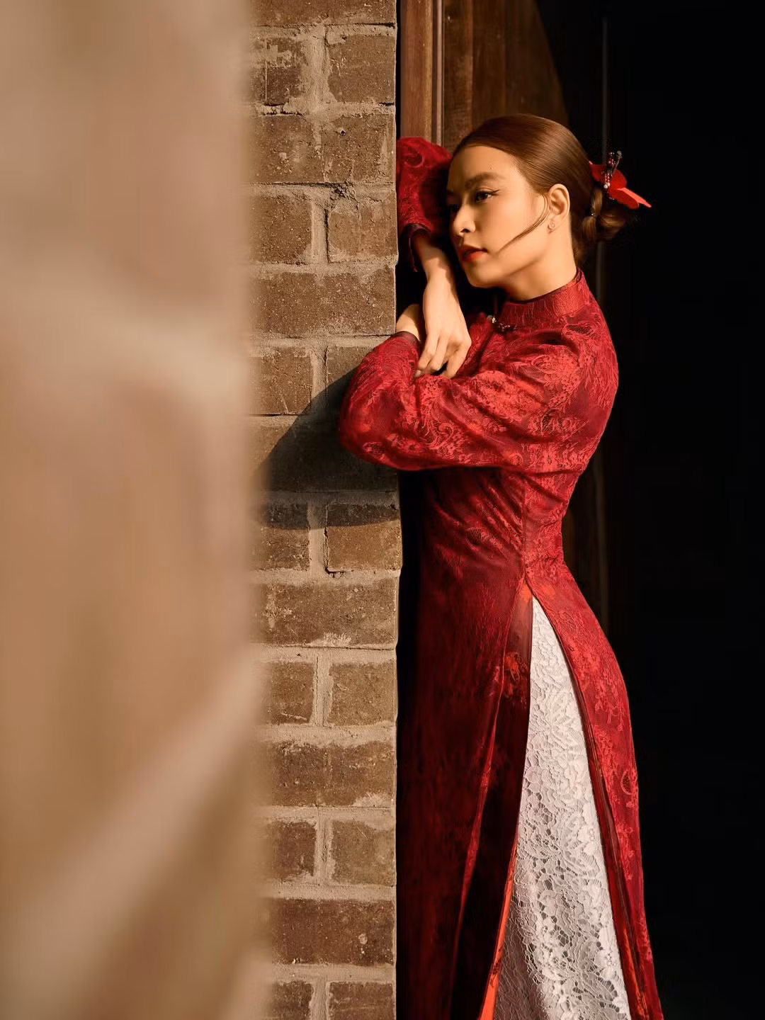 Bối cảnh bộ ảnh của Hoàng Thùy Linh cũng góp phần tạo nên sức hút đặc biệt. Những bậc thềm đá, tường gạch cổ và kiến trúc đậm dấu ấn truyền thống mang lại cảm giác trầm mặc, cổ kính, hòa quyện cùng tà áo dài thướt tha.