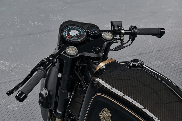 Vẻ ngoài toát lên sự sang trọng với sọc lá vàng thật được phủ bóng màu xám chạy dọc thân xe, nổi bật trên nền đen bóng và đen mờ. Huy hiệu bình xăng bằng đồng thau đúc thủ công – chi tiết được kế thừa trực tiếp từ bản độ nguyên mẫu – trở thành điểm nhấn độc đáo.