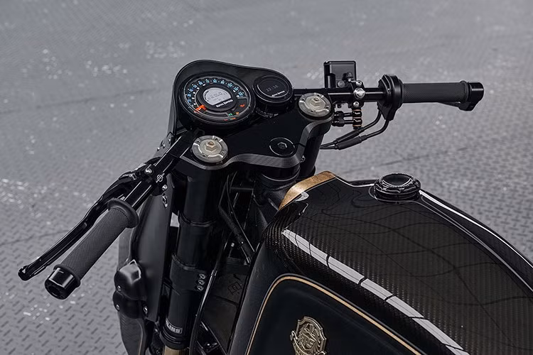 Vẻ ngoài toát lên sự sang trọng với sọc lá vàng thật được phủ bóng màu xám chạy dọc thân xe, nổi bật trên nền đen bóng và đen mờ. Huy hiệu bình xăng bằng đồng thau đúc thủ công – chi tiết được kế thừa trực tiếp từ bản độ nguyên mẫu – trở thành điểm nhấn độc đáo.