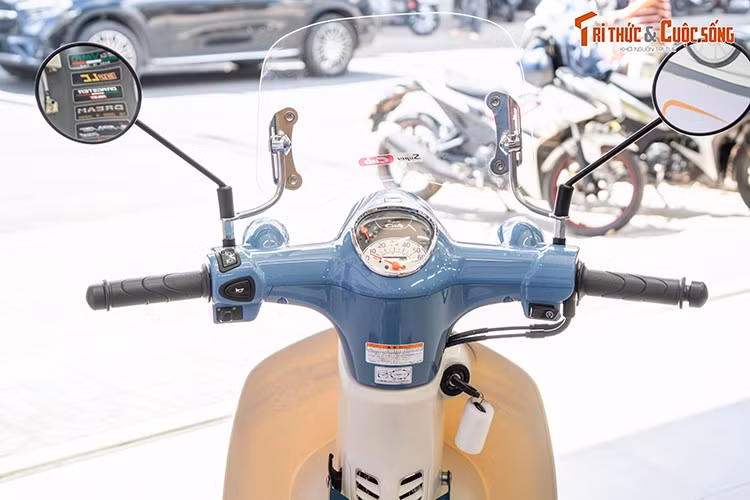 Điểm nhấn ở đầu xe là cụm đồng hồ analog tạo hình giọt nước giống với những mẫu Honda Super Cub 50cc cổ điển. Phiên bản cuối cùng của mẫu xe số huyền thoại thương hiệu Honda tiếp tục duy trì các trang bị ở mức cơ bản tại khu vực ghi-đông. Gương chiếu hậu dạng tròn cổ điển.