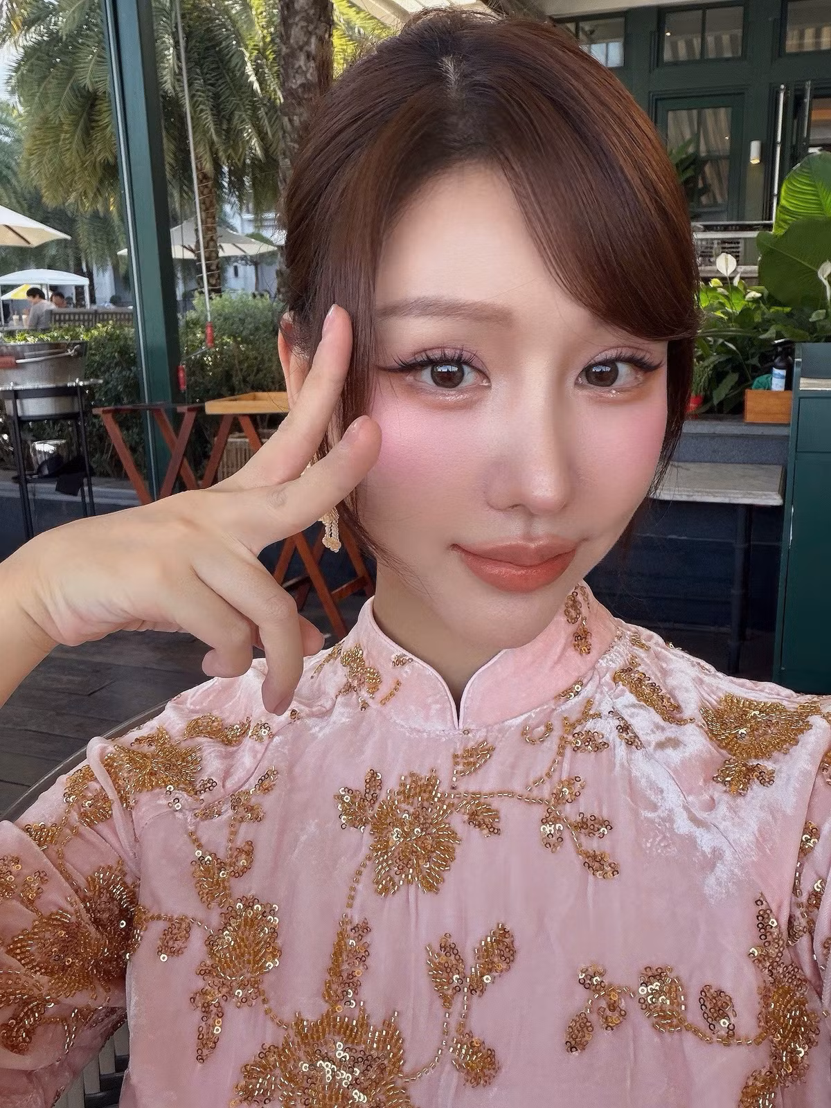 Ở lần xuất hiện này, Min lựa chọn áo dài gam hồng pastel nhẹ nhàng, được thêu họa tiết ánh kim tinh xảo. Thiết kế cổ cao, tay dài mang phom dáng truyền thống, kết hợp cùng chất liệu mềm rũ giúp tổng thể trang phục vừa nền nã vừa tôn lên vóc dáng thanh mảnh của nữ ca sĩ. Sự tiết chế trong màu sắc nhưng chăm chút ở từng đường thêu khiến bộ áo dài trở nên nổi bật mà không hề phô trương.