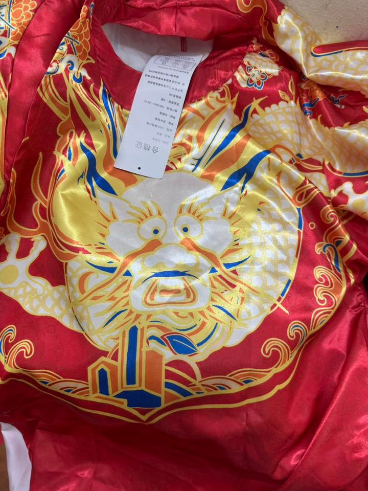 Chưa hết, ngay cả phần tag áo cũng khiến chính chủ phải đau não khi được thiết kế như một… lá bùa, đặt cạnh hình rồng càng tăng thêm độ khó hiểu cho trang phục.