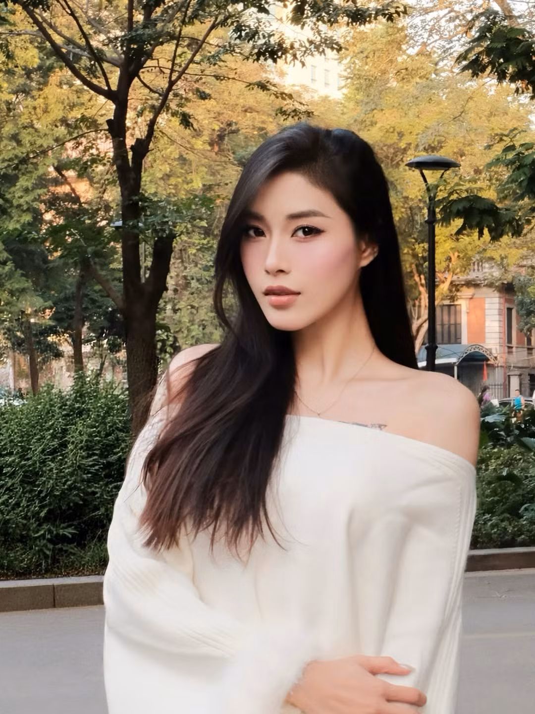 Chiếc áo lệch vai màu trắng mang đến vẻ đẹp vừa tinh khôi, vừa gợi cảm một cách tinh tế. Những chi tiết lông mịn ở tay áo tạo điểm nhấn mềm mại, khiến phong cách của cô trở nên sang trọng nhưng vẫn trẻ trung. Vóc dáng cân đối cùng đôi chân thon gọn càng giúp Thu Huyền thêm nổi bật giữa khung cảnh thiên nhiên xanh mát.