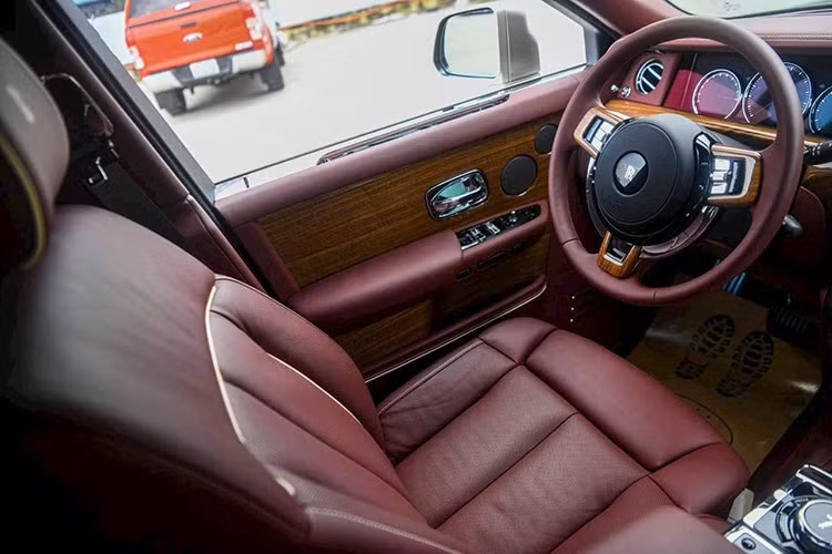 Tiến vào bên trong khoang lái, chiếc xe siêu sang Rolls-Royce Phantom thế hệ thứ 8 này được phủ màu sắc là đỏ mận, cùng với nhiều chi tiết ốp gỗ quý hiếm. Đáng chú ý, xe có trang bị tùy chọn vách ngăn cho hàng ghế trước và sau, loại này dạng kính, có rèm che.