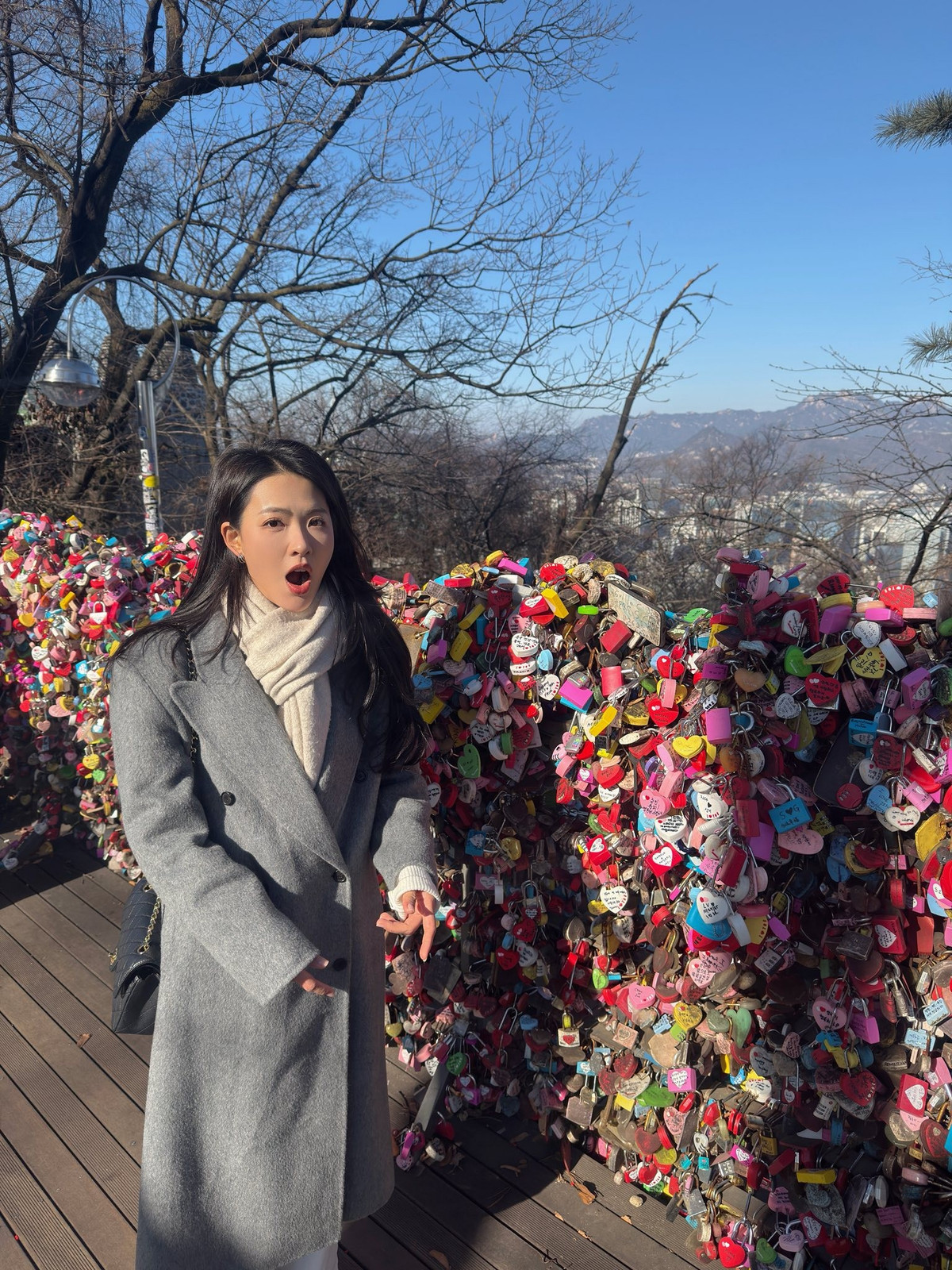 Nữ diễn viên chọn áo khoác dáng dài gam xám trung tính, kết hợp khăn len sáng màu, vừa giữ ấm vừa tạo tổng thể thanh lịch, tinh tế.