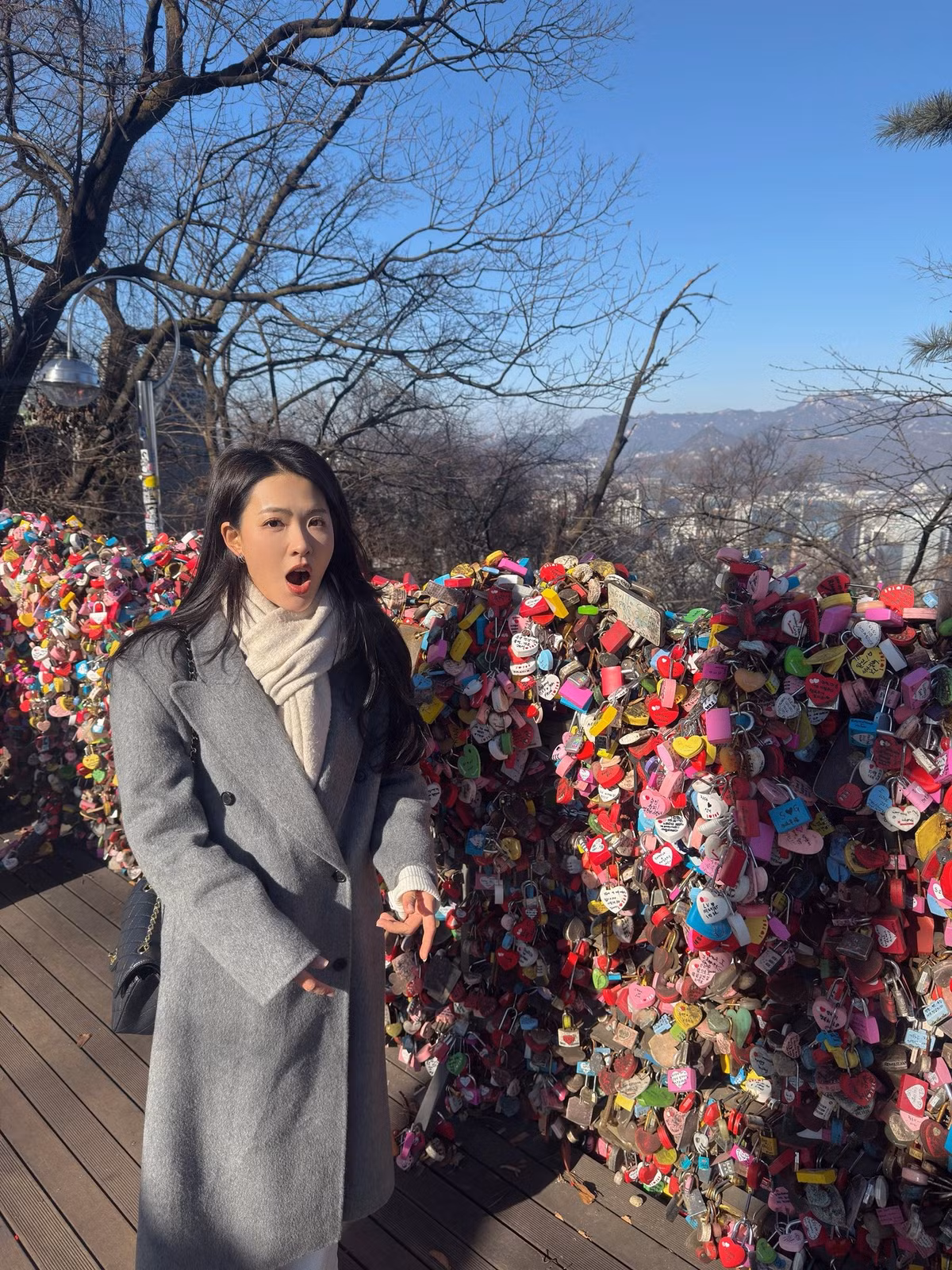 Nữ diễn viên chọn áo khoác dáng dài gam xám trung tính, kết hợp khăn len sáng màu, vừa giữ ấm vừa tạo tổng thể thanh lịch, tinh tế.