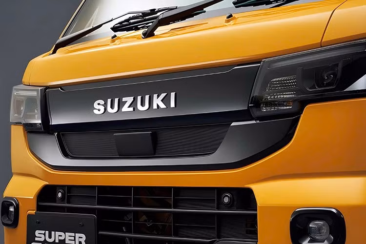Thay đổi lớn nhất của Suzuki Carry 2026 về mặt ngoại hình nằm ở phía trước, nơi phần mũi xe được thiết kế lại với đèn pha bố trí nằm ngang. Đèn pha mới kết hợp với lưới tản nhiệt mỏng hơn và hốc hút gió trên cản trước lớn hơn.