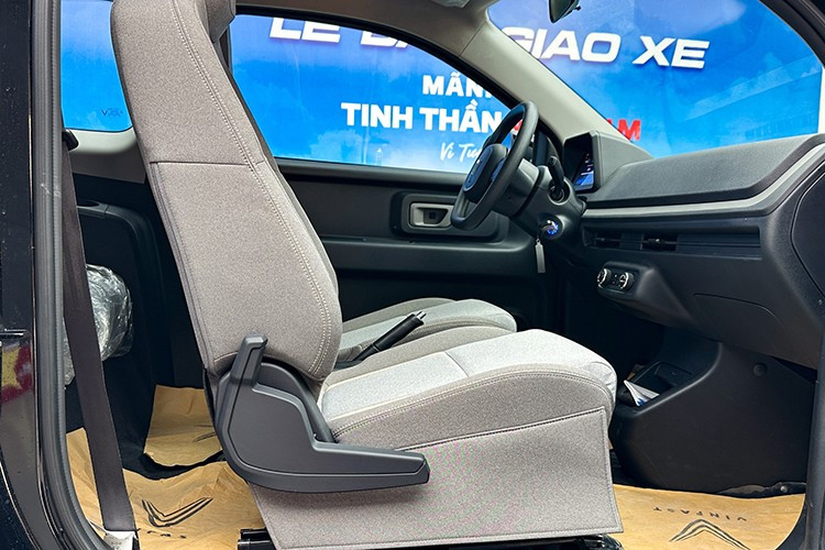 Giữa 2 ghế hàng đầu Minio Green là khu vực bố trí phanh tay cơ, khay đựng cốc cùng các phím vật lý điều chỉnh lên/xuống kính. Xe được trang bị cụm phím vật lý điều chỉnh hệ thống điều hòa không khí, khóa cửa xe và tắt/mở đèn hazard đặt tại trung tâm táp-lô.