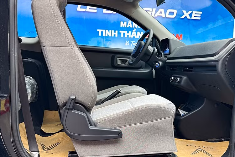 Giữa 2 ghế hàng đầu Minio Green là khu vực bố trí phanh tay cơ, khay đựng cốc cùng các phím vật lý điều chỉnh lên/xuống kính. Xe được trang bị cụm phím vật lý điều chỉnh hệ thống điều hòa không khí, khóa cửa xe và tắt/mở đèn hazard đặt tại trung tâm táp-lô.