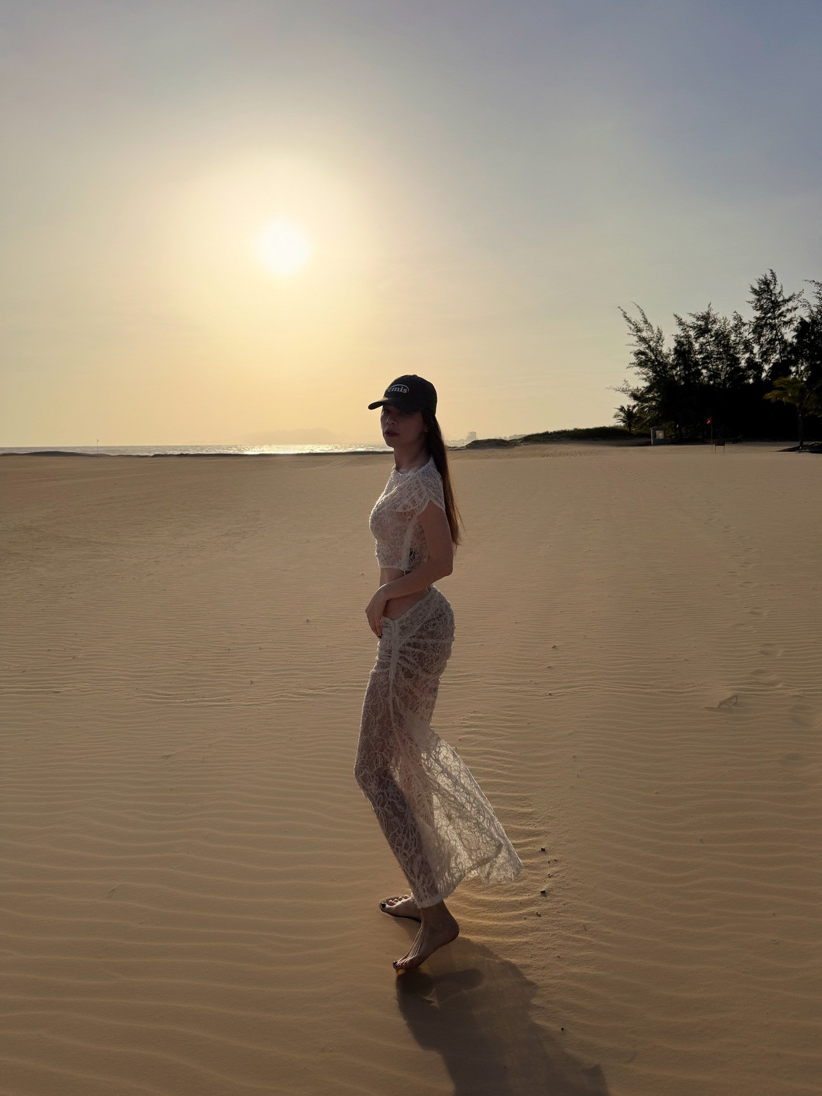 Diện set đồ trắng xuyên thấu tinh tế trên bãi cát vàng, 'nữ hoàng giải trí' Hồ Ngọc Hà khiến người hâm mộ không khỏi trầm trồ trước vóc dáng thon gọn, săn chắc cùng thần thái cuốn hút khó trộn lẫn.