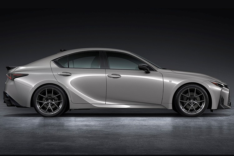 Ngoại thất của IS 2026 được tinh chỉnh theo ngôn ngữ “spindle body” mới của Lexus. Phần đầu xe gây chú ý với lưới tản nhiệt lớn dạng lưới mắt cáo, nối liền cùng cụm đèn pha quen thuộc, trong khi logo được chuyển lên vị trí mới trên thanh nẹp đồng màu thân xe.