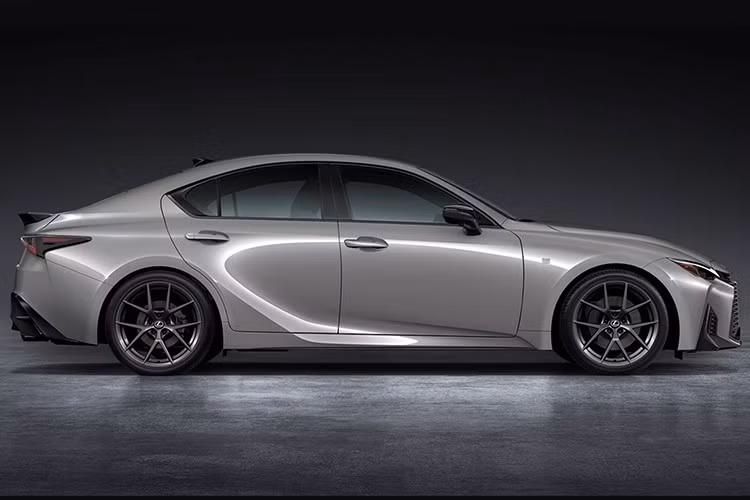 Ngoại thất của IS 2026 được tinh chỉnh theo ngôn ngữ “spindle body” mới của Lexus. Phần đầu xe gây chú ý với lưới tản nhiệt lớn dạng lưới mắt cáo, nối liền cùng cụm đèn pha quen thuộc, trong khi logo được chuyển lên vị trí mới trên thanh nẹp đồng màu thân xe.