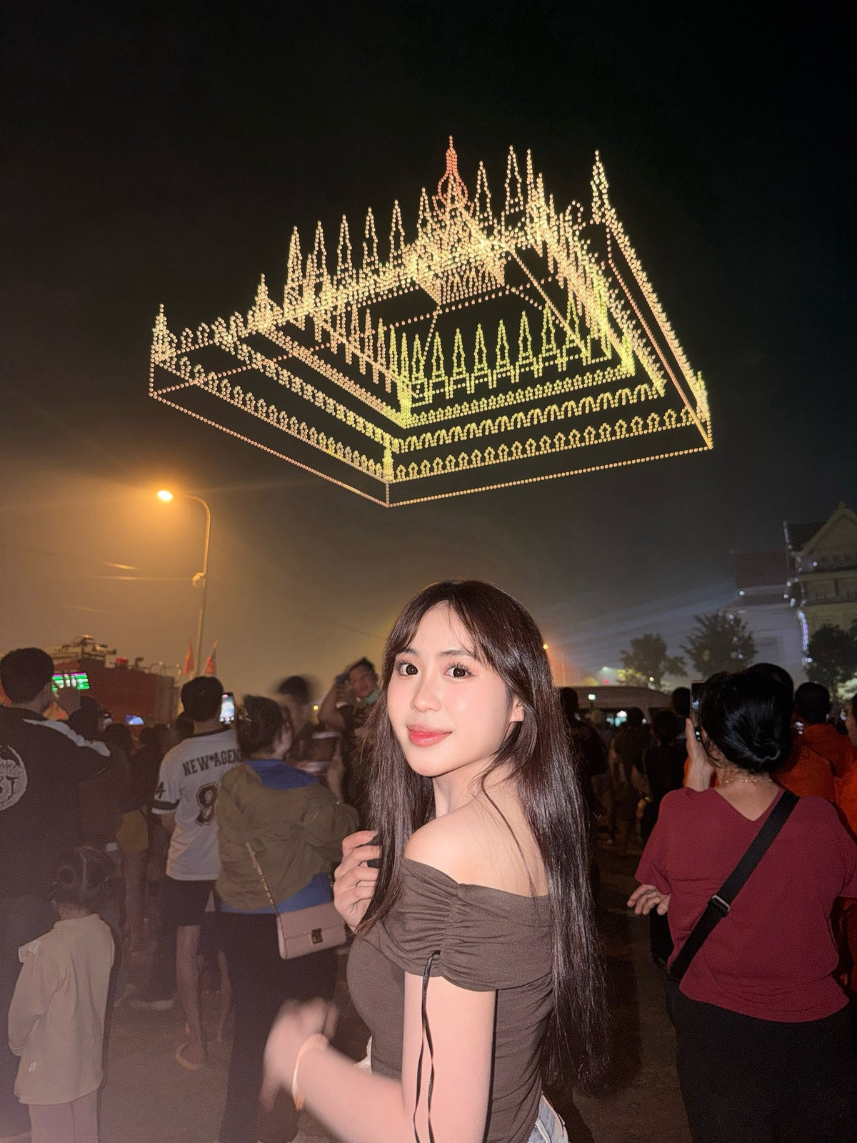 Nét đẹp của cô càng trở nên rực rỡ dưới ánh sáng lung linh của pháo hoa và hàng nghìn chiếc drone tạo hình trên bầu trời. Từ lá cờ Lào, công trình kiến trúc đặc trưng đến hình tượng voi trắng – biểu tượng văn hoá Lào – tất cả đều tạo nên phông nền hoàn hảo để tôn lên thần thái cuốn hút của Maysaa.