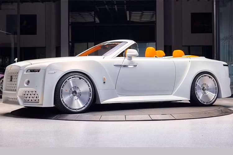 Không dừng lại ở đó, Venuum còn gắn thêm đèn phụ dạng tròn nhô ra từ cản trước cho xe. Trong khi đó, đèn pha nguyên bản bị che khuất một phần bởi bộ bodykit mới. Ngay cả biểu tượng "thiếu phụ bay" Spirit of Ecstasy cũng được tái thiết kế và sơn trắng, đi kèm logo Rolls-Royce màu cam tương phản.