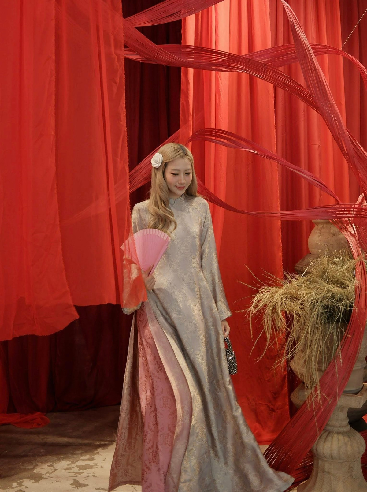 Thiết kế suông dài, tay rộng tạo cảm giác thướt tha, mềm mại theo từng chuyển động. Phần tà áo khẽ mở để lộ lớp quần hồng pastel bên trong giúp tổng thể thêm phần nữ tính, bay bổng mà không kém phần hiện đại.