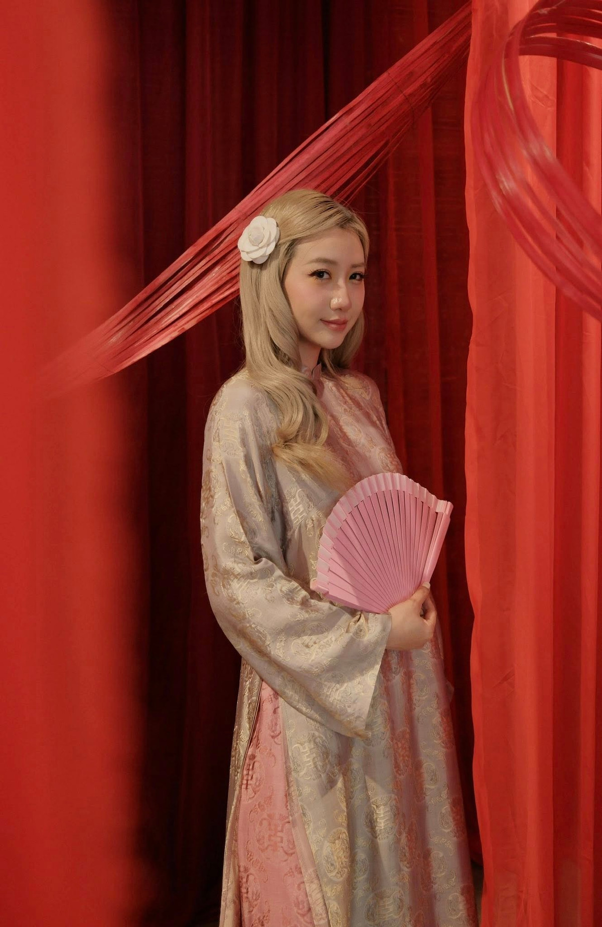 Không cần phụ kiện cầu kỳ, Kiều Ly Phạm chỉ khéo léo điểm xuyết bằng chiếc quạt tay tông hồng đồng điệu cùng lớp quần bên trong.