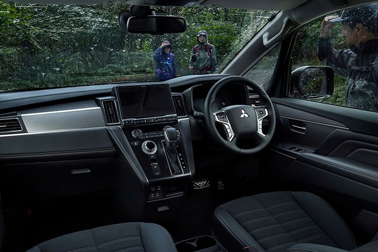 Bên trong khoang lái, Mitsubishi Delica D:5 2026 có nâng cấp công nghệ đáng chú ý nhất là bảng đồng hồ kỹ thuật số 8 inch mới. Trang bị này kết hợp với màn hình giải trí trung tâm 10,1 inch như cũ và vẫn đặt trên bệ tì tay trung tâm nghiêng. Bố cục nội thất của xe cũng không thay đổi, vẫn đi kèm 3 hàng ghế và chở tối đa 8 người.