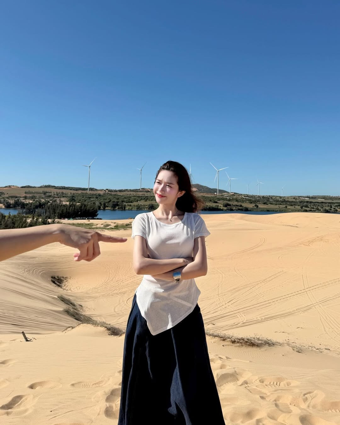 Trang phục đơn giản giúp gái xinh gốc Điện Biên hòa mình trọn vẹn vào thiên nhiên, đồng thời tôn lên vóc dáng mảnh mai và khí chất nhẹ nhàng. Mái tóc dài uốn lơi buông xõa tự nhiên trong gió, kết hợp cách tạo dáng thoải mái giữa đồi cát mênh mông, mang đến cảm giác tự do, thư thái.