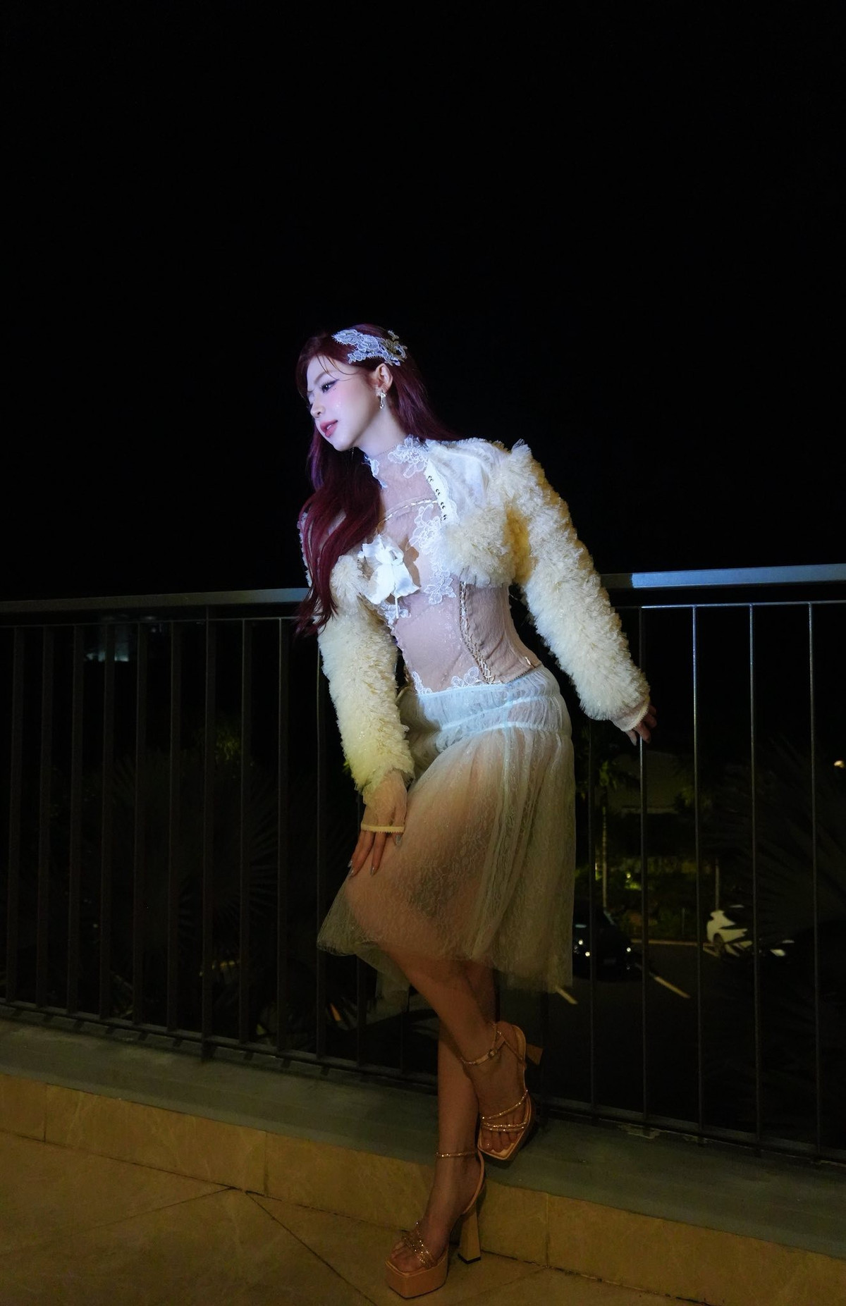 Lớp váy voan nhẹ nhàng phủ bên ngoài mang lại sự tinh tế, còn áo khoác lông mềm tạo hiệu ứng thị giác sang trọng. Bộ trang phục xuyên thấu được xử lý khéo léo, giúp Liz Kim Cương vừa nổi bật vừa không mất đi sự thanh lịch vốn có.