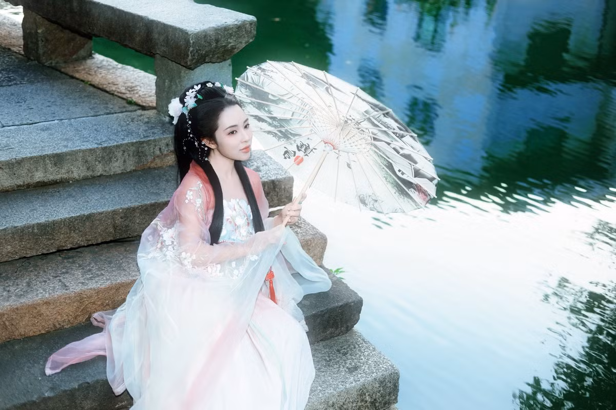 Bảo Trâm idol gây ấn tượng mạnh với vẻ đẹp trong trẻo và thanh tao. Khuôn mặt nhỏ nhắn, làn da trắng mịn cùng ánh mắt dịu dàng khiến cô toát lên khí chất vừa cổ điển vừa đài các. Mái tóc đen dài được búi nhẹ, điểm xuyết hoa trắng và chuỗi trân châu nhỏ tạo cảm giác mềm mại và tinh khôi.