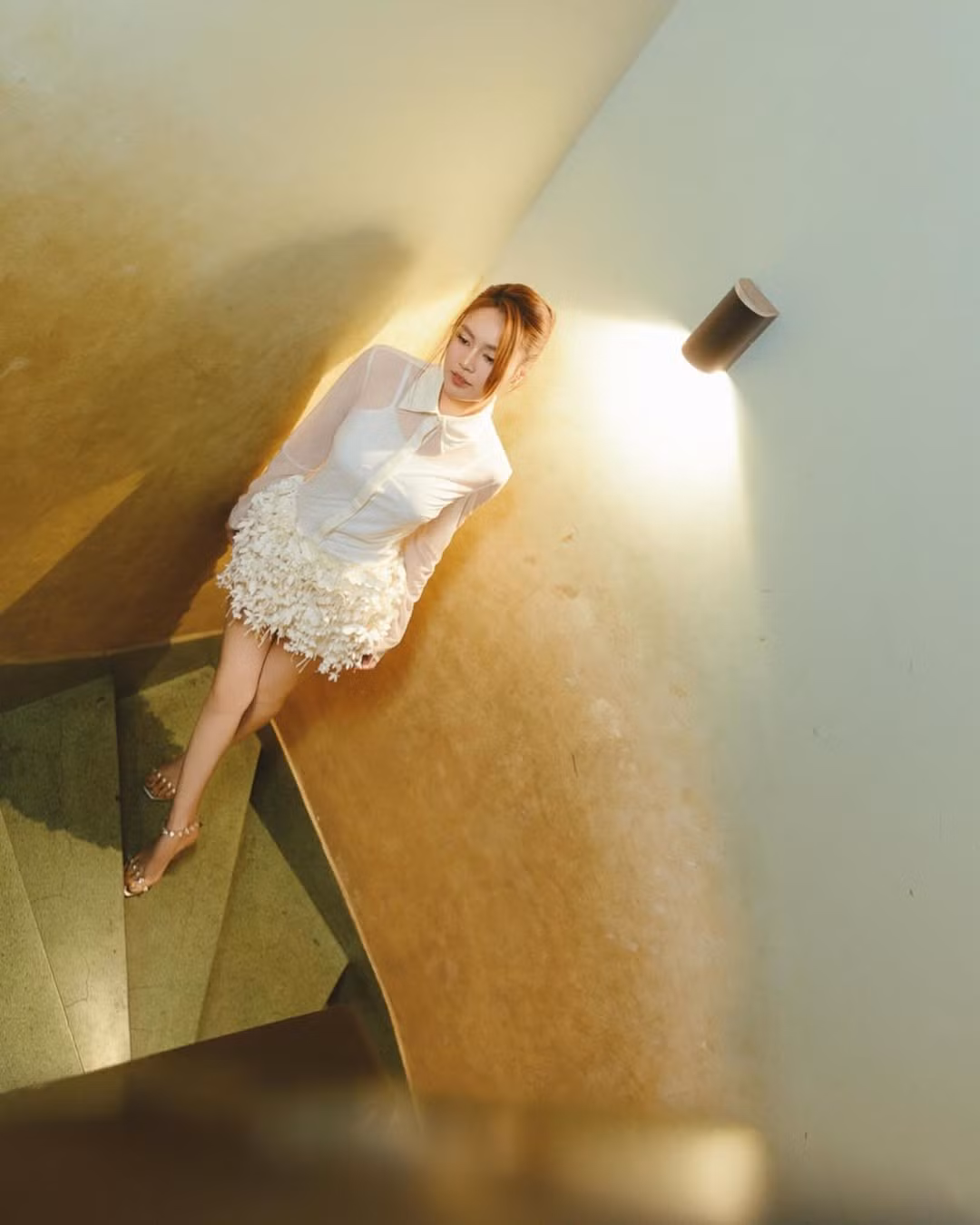 Những tông vàng ấm của không gian cầu thang cổ điển tạo nên hiệu ứng thị giác đẹp mắt, làm bật lên làn da sáng mịn cùng vóc dáng mảnh mai của nữ diễn viên.