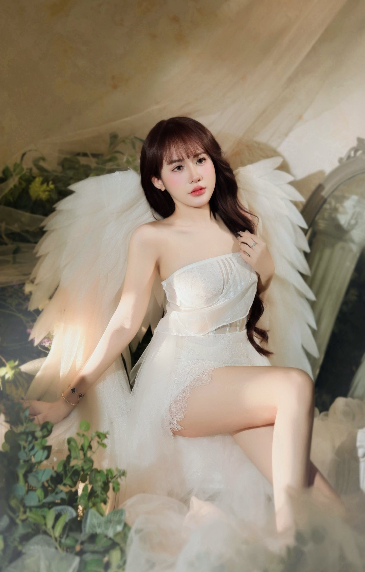 Trong bộ cánh trắng tinh khôi, Lê Tuyết Anh hóa thân thành một “thiên thần” đúng nghĩa với đôi cánh lớn mềm mại phía sau lưng. Thiết kế váy ôm nhẹ phần thân trên, kết hợp chất liệu voan, ren mỏng manh giúp tôn lên làn da trắng mịn cùng vóc dáng cân đối của người đẹp xứ Thanh. Đường cắt tinh tế vừa đủ gợi cảm nhưng không phô trương, tạo nên tổng thể hài hòa giữa nét trong trẻo và quyến rũ.