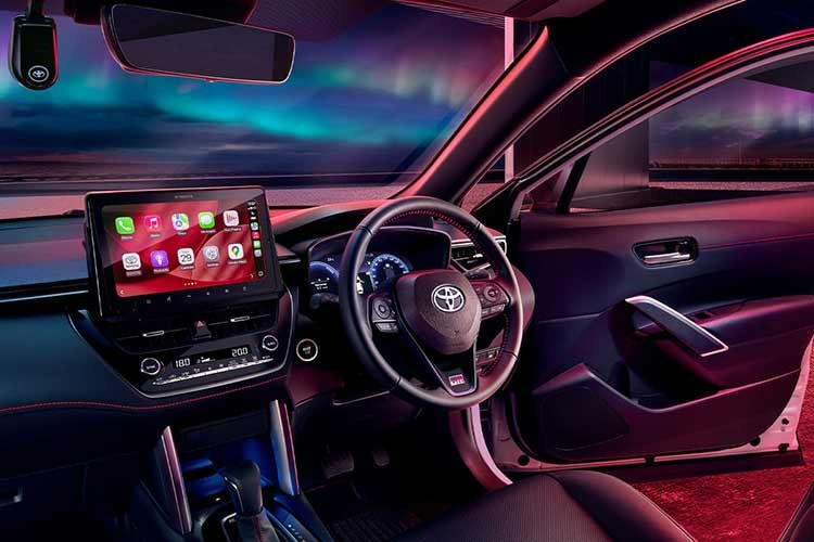 Bên trong cabin, Corolla Cross HEV GR Sport 2026 tiếp tục sử dụng tông đen chủ đạo nhưng được bổ sung các chi tiết chỉ đỏ trên bảng táp-lô và ốp cửa, thay cho chỉ trắng trước đó. Đây là sự nâng cấp nhỏ nhưng giúp tổng thể nội thất đồng nhất và đậm chất thể thao hơn.