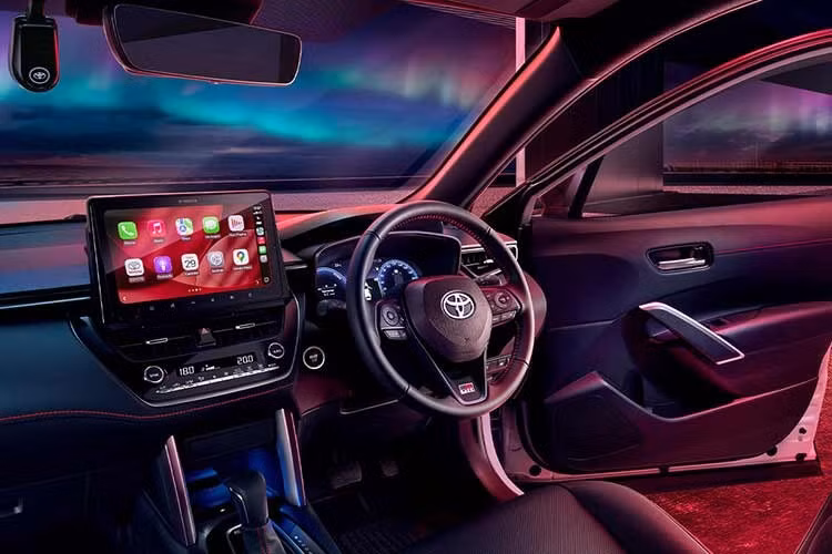 Bên trong cabin, Corolla Cross HEV GR Sport 2026 tiếp tục sử dụng tông đen chủ đạo nhưng được bổ sung các chi tiết chỉ đỏ trên bảng táp-lô và ốp cửa, thay cho chỉ trắng trước đó. Đây là sự nâng cấp nhỏ nhưng giúp tổng thể nội thất đồng nhất và đậm chất thể thao hơn.