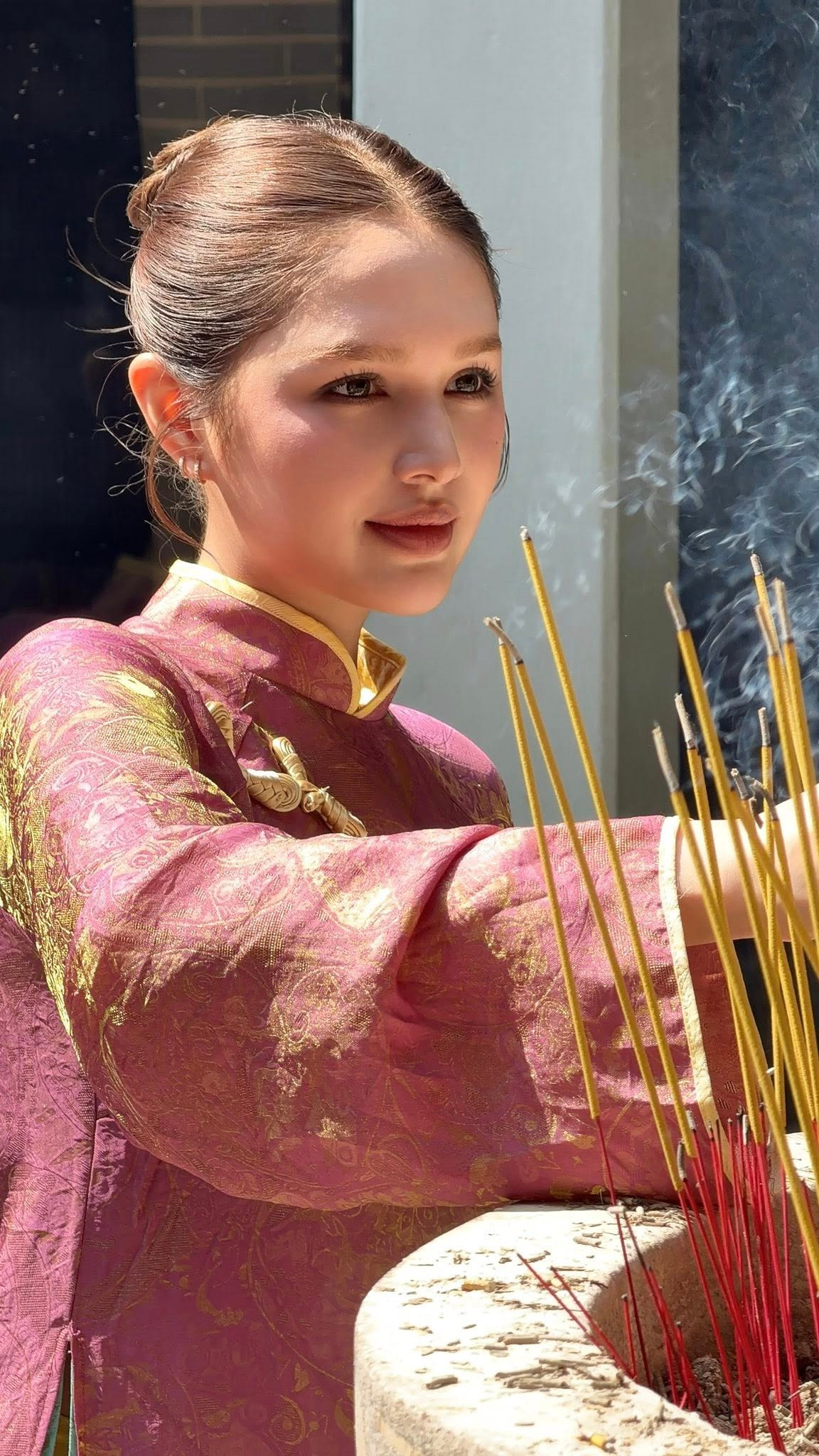 Không còn hình ảnh một hot girl cá tính, thời thượng thường thấy trên mạng xã hội, Xoài Non trong áo dài mang dáng vẻ trầm lắng, dịu dàng và trưởng thành hơn. Ánh nhìn nhẹ nhàng, nụ cười kín đáo nhưng đủ ấm áp tạo cảm giác bình yên, rất phù hợp với không gian tâm linh mà cô xuất hiện.