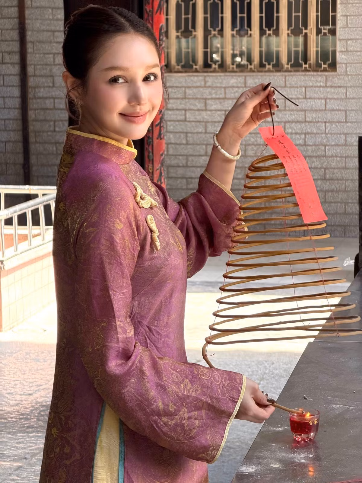 Trong những khung hình được chia sẻ, Xoài Non lựa chọn áo dài gam tím trầm pha ánh vàng nhẹ, họa tiết cổ điển tinh tế, tôn lên làn da trắng mịn và vóc dáng mảnh mai.