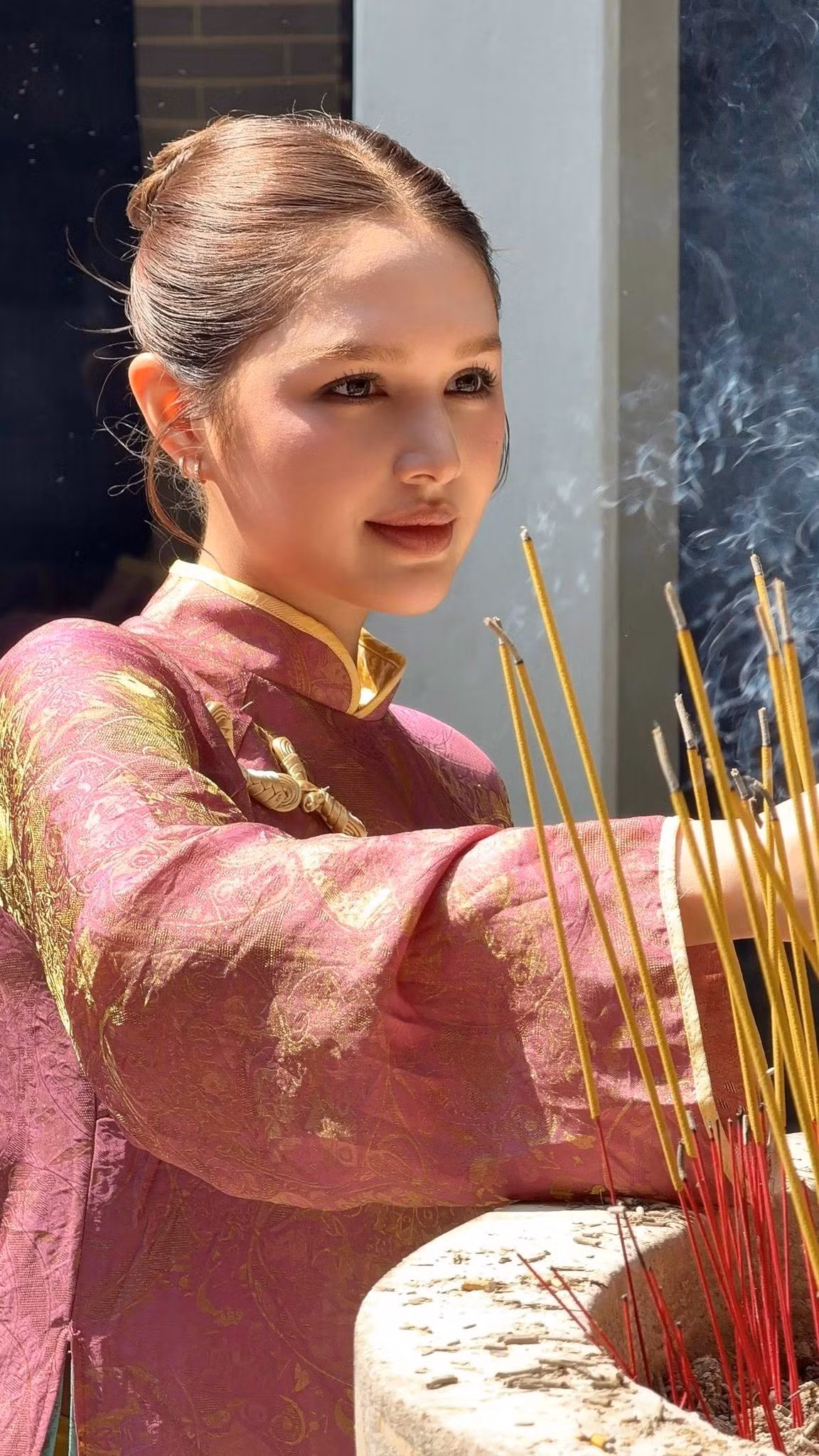 Không còn hình ảnh một hot girl cá tính, thời thượng thường thấy trên mạng xã hội, Xoài Non trong áo dài mang dáng vẻ trầm lắng, dịu dàng và trưởng thành hơn. Ánh nhìn nhẹ nhàng, nụ cười kín đáo nhưng đủ ấm áp tạo cảm giác bình yên, rất phù hợp với không gian tâm linh mà cô xuất hiện.