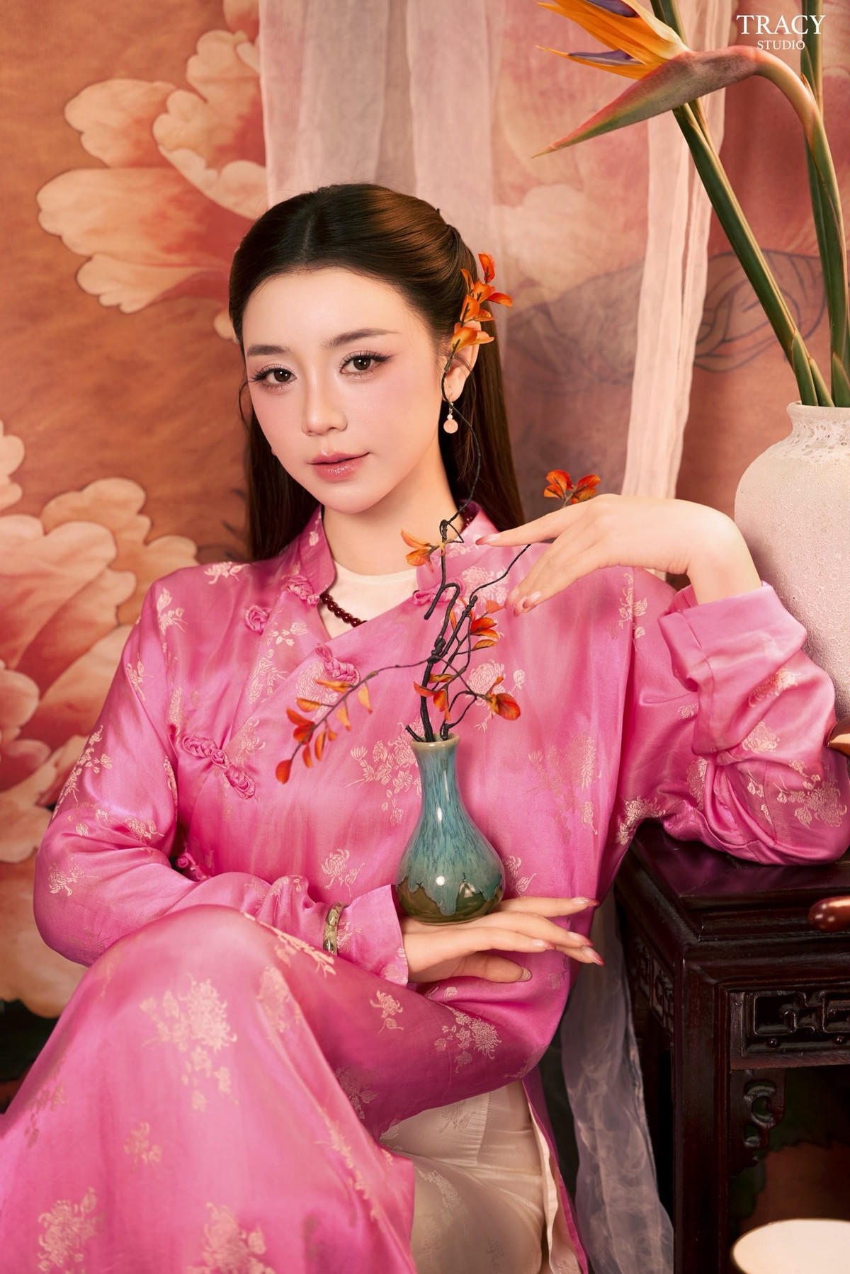 Trong bộ áo dài lụa hồng ánh nhũ, Quỳnh Kool toát lên thần thái mềm mại, đậm chất Á Đông. Phần cổ cao kín đáo, phom dáng thướt tha giúp tôn lên vóc dáng thanh mảnh cùng làn da trắng mịn của nữ diễn viên. Gương mặt nhỏ nhắn, sống mũi cao, đôi mắt to tròn long lanh và bờ môi hồng tự nhiên càng khiến tổng thể nhan sắc thêm phần hài hòa.