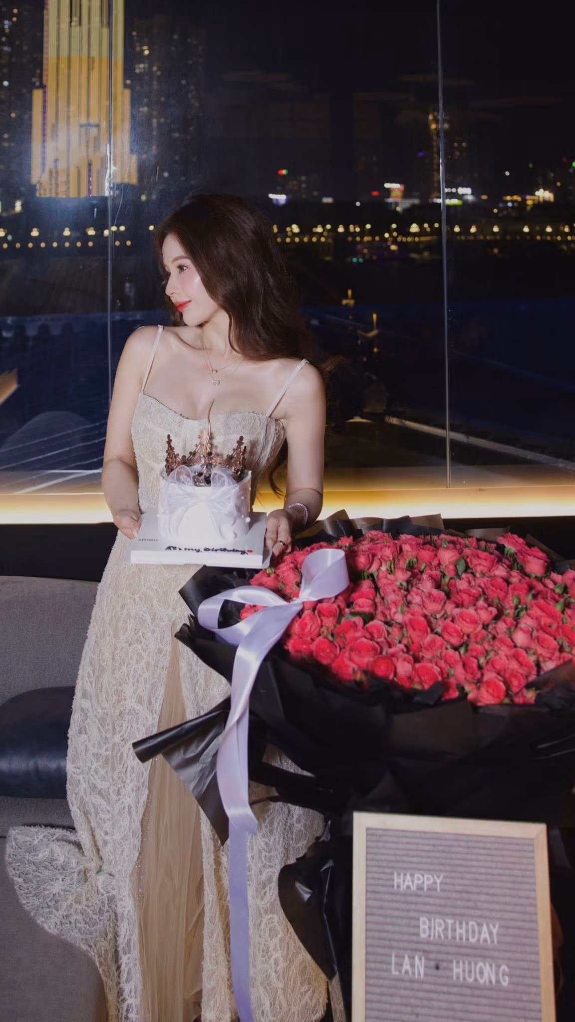 Trong ngày sinh nhật, Lan Hương khoác lên mình chiếc đầm ren hai dây màu kem (hoặc trắng ngà) tinh tế, với phần thân váy được may bằng chất liệu ren họa tiết cầu kỳ, tôn lên đường nét thanh mảnh và vẻ ngoài dịu dàng, quý phái.