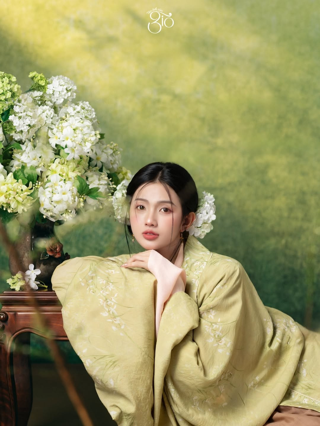 Mái tóc được vấn gọn gàng, điểm xuyết hoa trắng tinh khôi, càng làm nổi bật khí chất nhẹ nhàng, thuần khiết. Từng cử chỉ, ánh nhìn đều toát lên vẻ điềm đạm, trang nhã – đúng tinh thần của trang phục truyền thống Việt Nam.