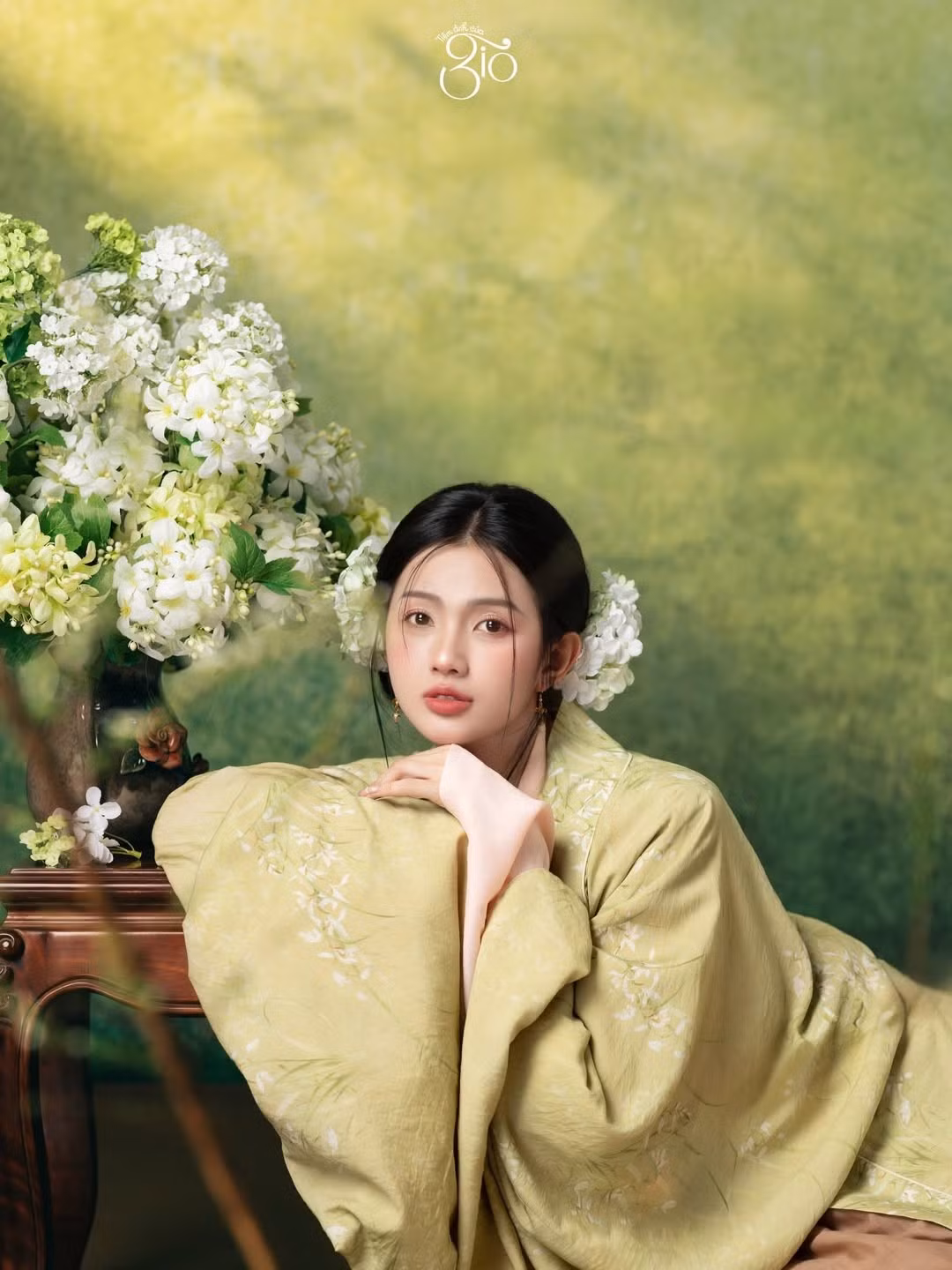 Mái tóc được vấn gọn gàng, điểm xuyết hoa trắng tinh khôi, càng làm nổi bật khí chất nhẹ nhàng, thuần khiết. Từng cử chỉ, ánh nhìn đều toát lên vẻ điềm đạm, trang nhã – đúng tinh thần của trang phục truyền thống Việt Nam.