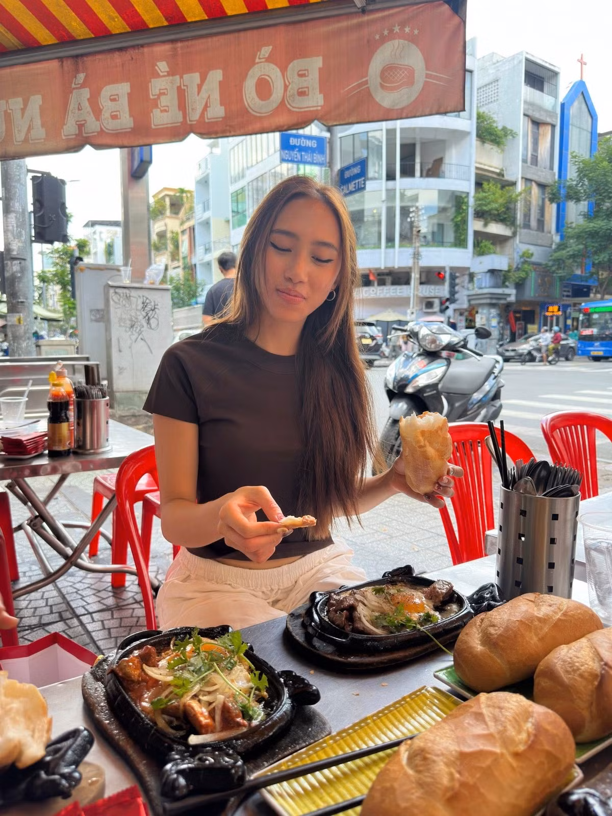 Trong các video được chia sẻ, Tylin tất bật đứng quầy, tay cầm sổ ghi món, miệng tập nói từng câu tiếng Việt còn vấp váp. Có lúc cao điểm, cô vừa nhận đơn, vừa lúng túng tính tiền cho khách, thậm chí đếm nhầm tiền lẻ rồi bật cười ngượng ngùng. Ở góc bếp, cô học cách đập trứng, đặt chảo, nghe tiếng xèo xèo của phần bò né nóng hổi, vừa làm vừa lắng nghe anh chị trong quán chỉ dẫn từng thao tác.