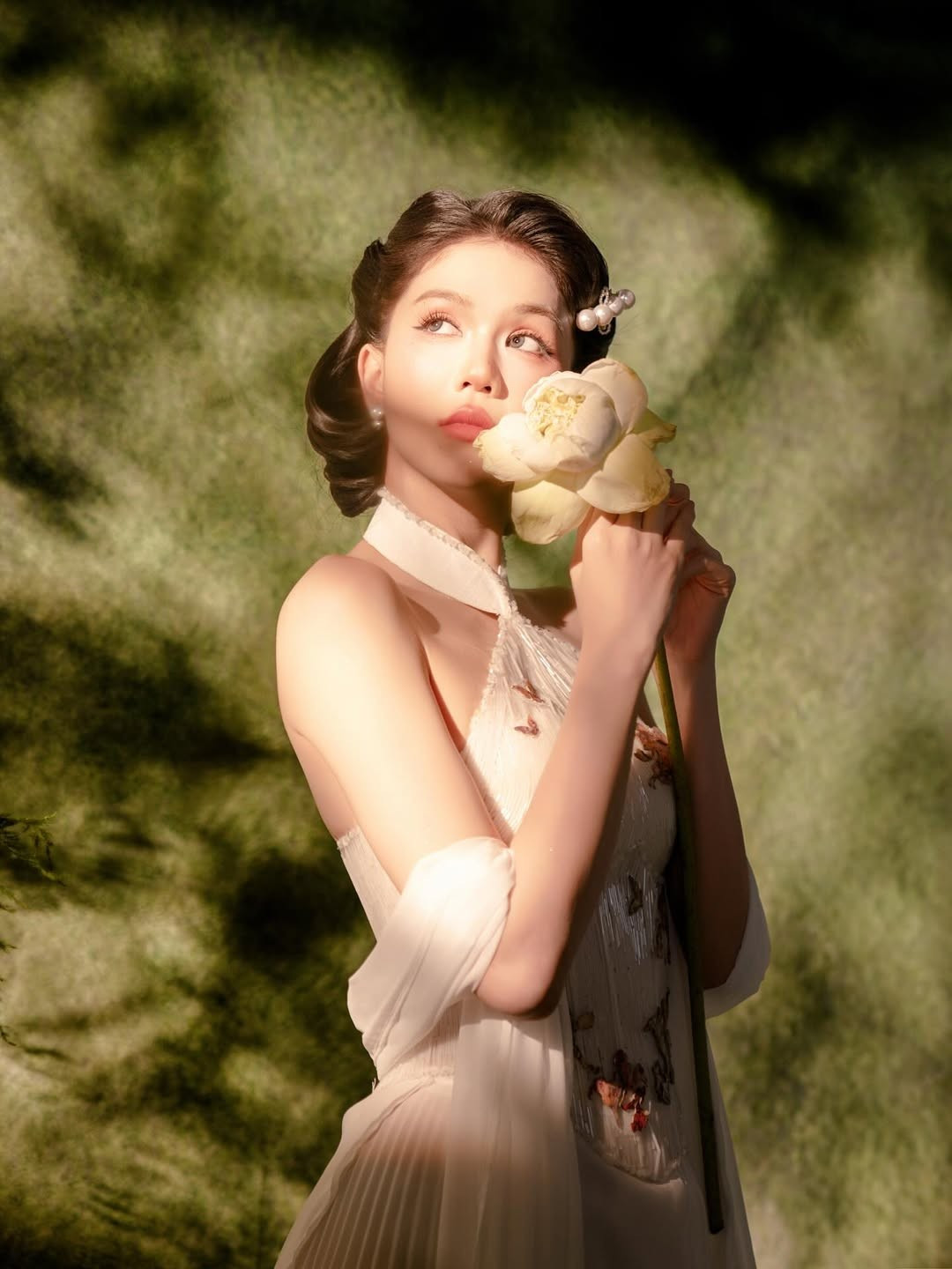 Mới đây, Ngọc Trinh thích thú khi đăng tải loạt ảnh dịu dàng, kín đáo, khác hẳn với hình tượng gợi cảm thường thấy. Cô diện một chiếc váy màu kem thanh lịch, tạo dáng bên một bình hoa sen trắng.