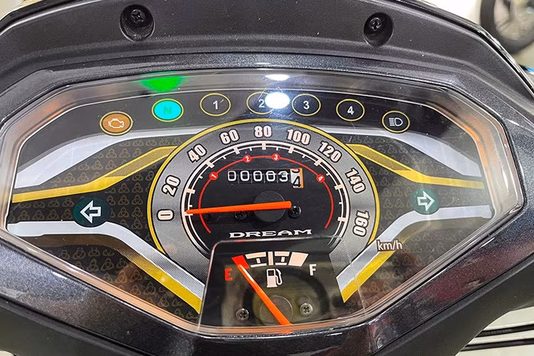 Cụm đồng hồ hiển thị trên Honda Dream NCX 2026 với các đường viền màu vàng trang trí, phân tách thành những khu vực hiển thị thông tin về tốc độ, mức nhiên liệu cùng hệ thống đèn báo… Viền nhựa bao quanh mặt đồng hồ cũng được thiết kế mới và phối màu xám bạc. Hệ thống khởi động vẫn dùng chìa khóa cơ, ổ khóa mở yên xe tích hợp trên phần sau thân xe.