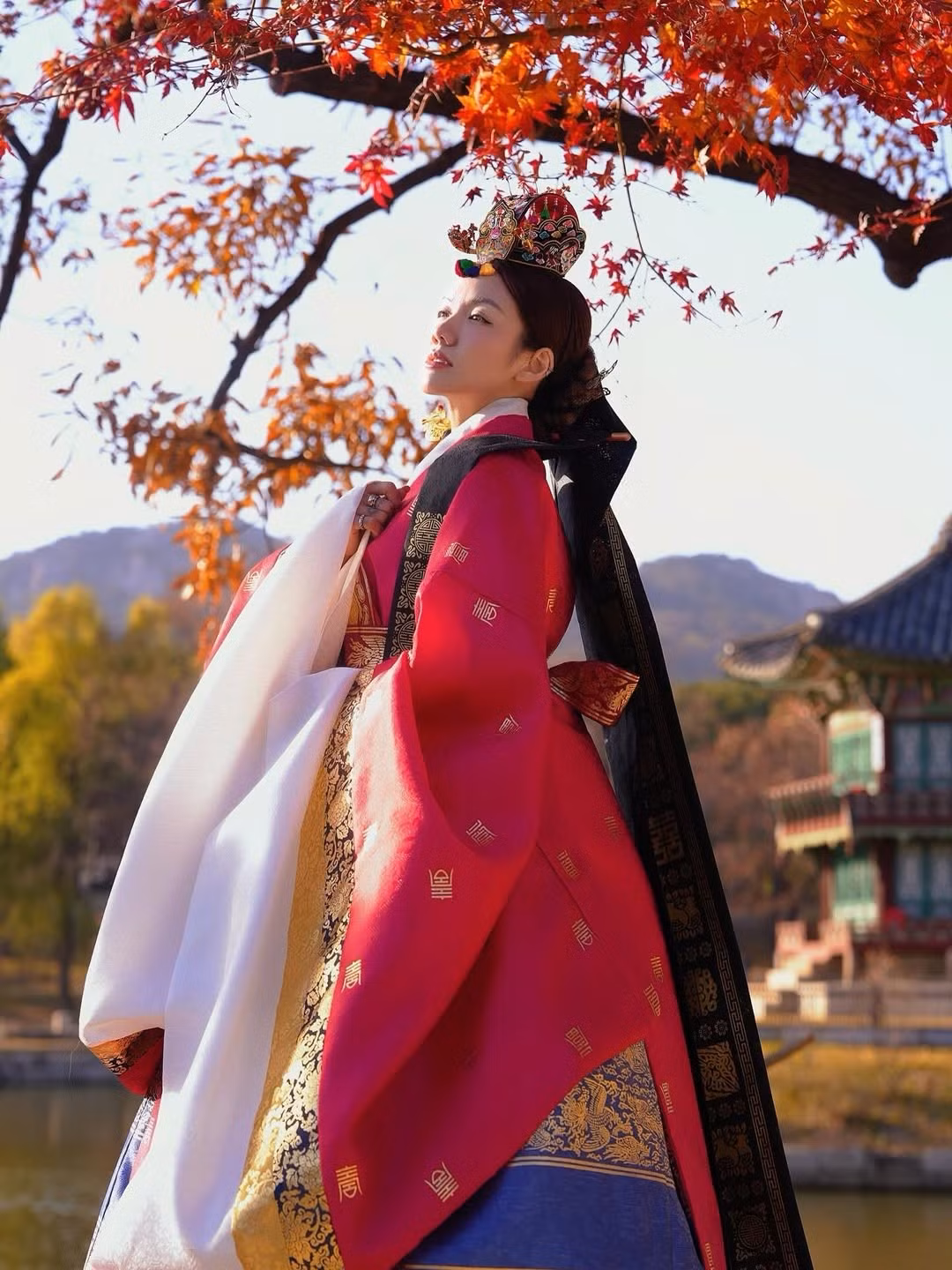 Trong những khung hình được chụp tại một cung điện cổ, Phương Ly xuất hiện trong bộ Hanbok cưới truyền thống Hàn Quốc, nổi bật với váy xanh – đỏ, đường viền thêu vàng sang trọng và tà áo trắng tinh khôi mềm mại.