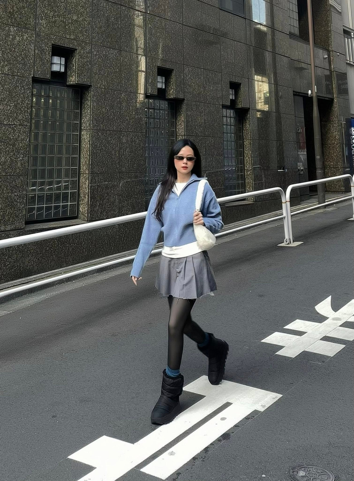 Trong chuyến dạo phố Tokyo, Midu lựa chọn outfit mang hơi hướng casual hiện đại với gam màu trung tính. Áo len dáng rộng kết hợp cùng chân váy ngắn xếp ly, quần tất đen và boots cổ thấp tạo nên tổng thể năng động nhưng vẫn giữ được nét nữ tính, thanh lịch.