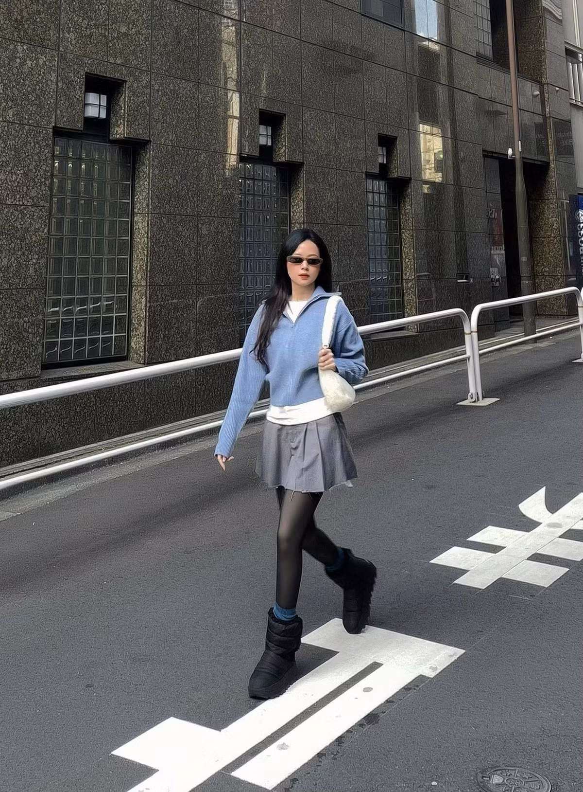 Trong chuyến dạo phố Tokyo, Midu lựa chọn outfit mang hơi hướng casual hiện đại với gam màu trung tính. Áo len dáng rộng kết hợp cùng chân váy ngắn xếp ly, quần tất đen và boots cổ thấp tạo nên tổng thể năng động nhưng vẫn giữ được nét nữ tính, thanh lịch.