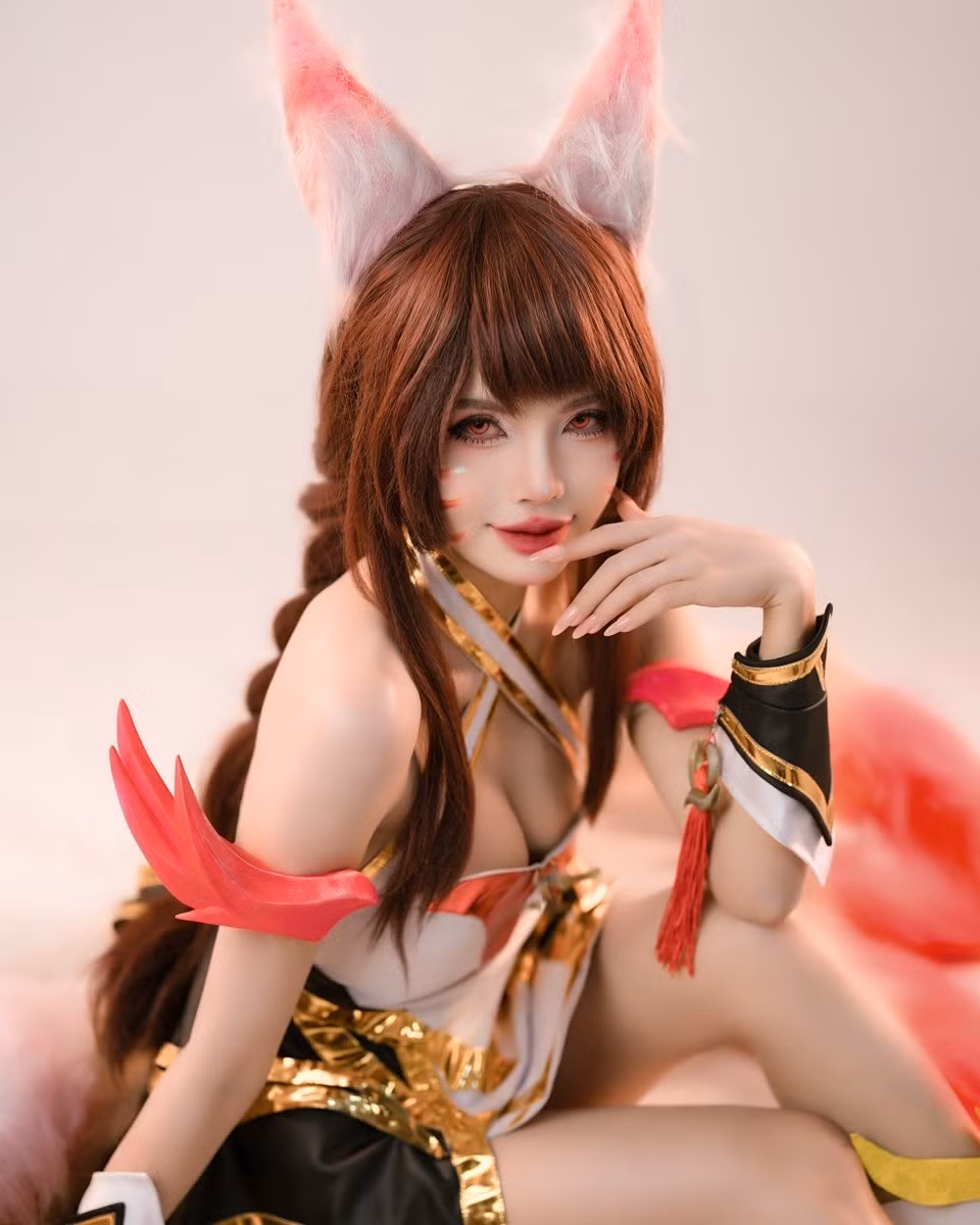 Điểm nhấn đắt giá của bộ ảnh chính là chín chiếc đuôi hồ ly bằng lông vũ cỡ lớn, xòe rộng màu trắng hồng vô cùng nổi bật, tạo nên một bối cảnh hoành tráng và huyền ảo.