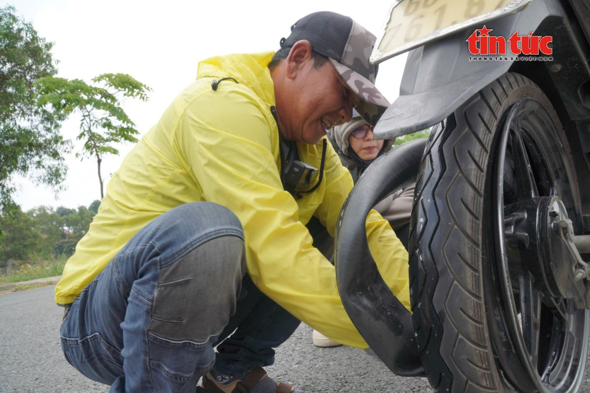 Một sinh viên bị thủng lốp, phải dắt xe được ông Long hỗ trợ thay ruột xe.