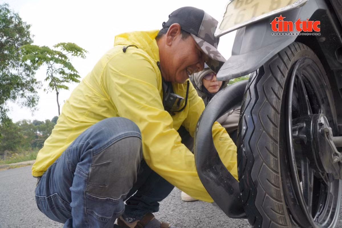 Một sinh viên bị thủng lốp, phải dắt xe được ông Long hỗ trợ thay ruột xe.